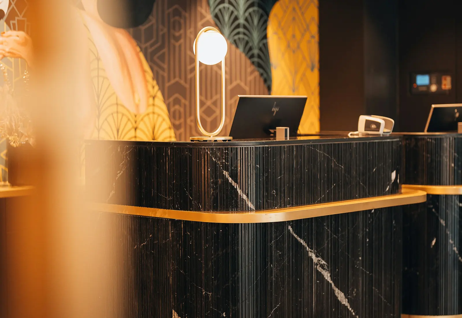 Black marble hotel reception desk with brass trim and a front desk computer