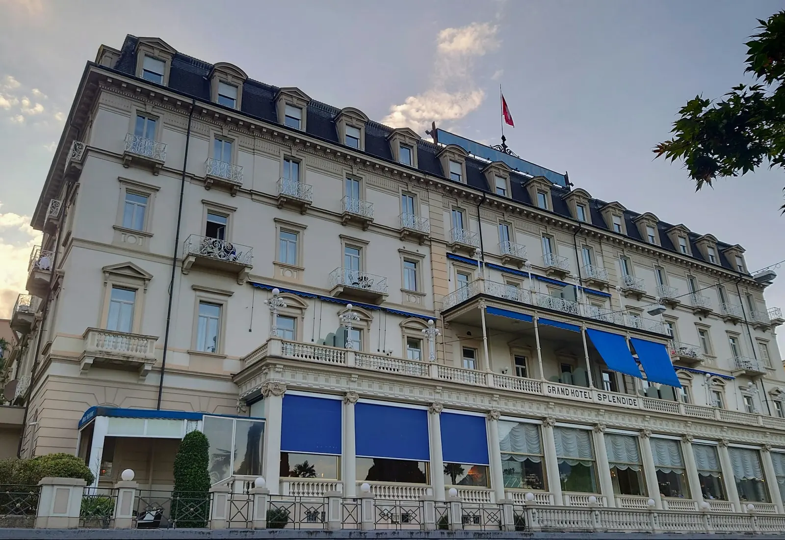 Facade of a grand hotel with balconies and blue awnings